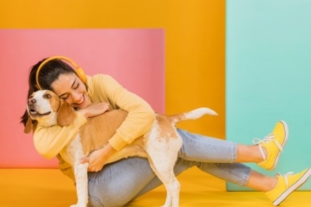 Mulher abrançando um cãozinho amarelo.